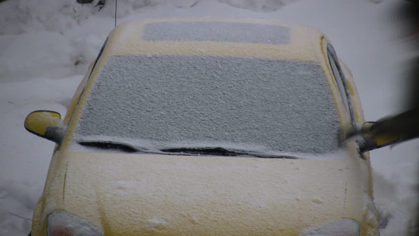A man is scraping the frost off of his car's windows (High Definition)