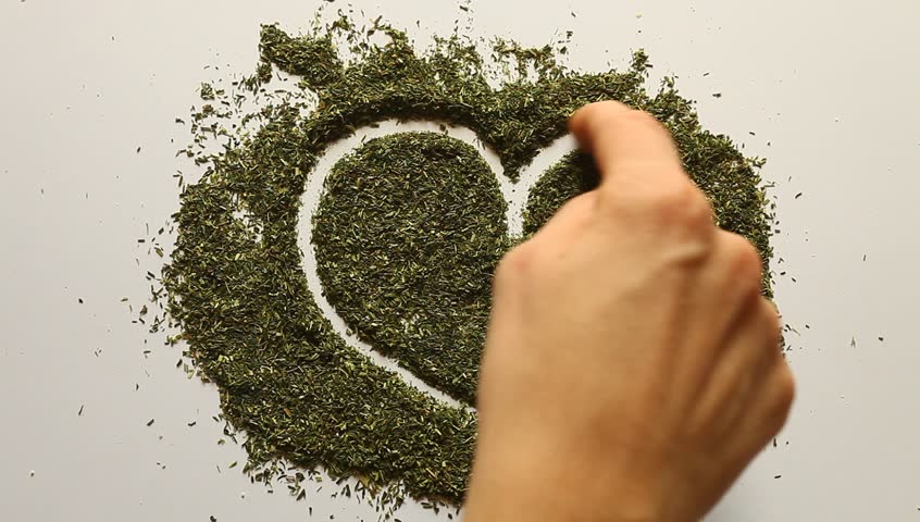 Young adult woman makes Valentines heart out of dry dill.
