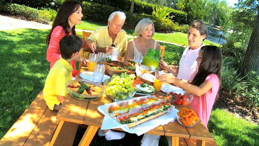 Fresh healthy food being eaten in the garden for lunch by three generations of family