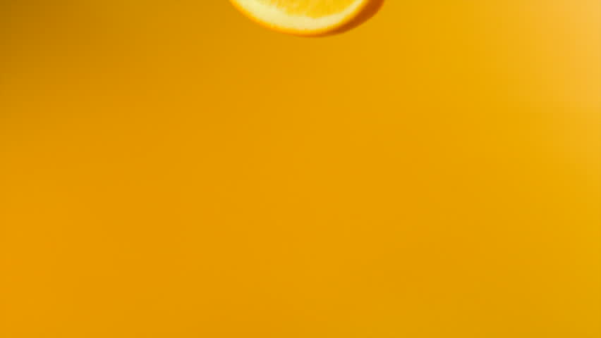 Sliced orange falling into orange juice shooting with high speed camera.