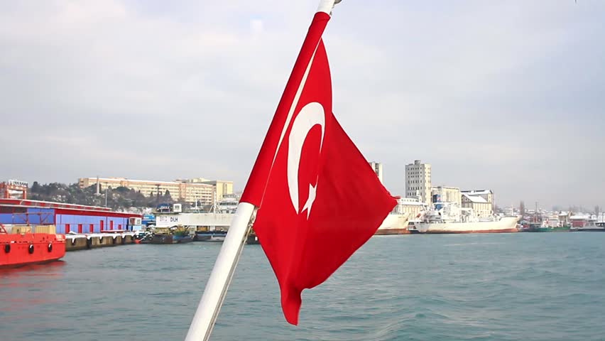 Seaport as seen from the waterside with a Turkish Flag waving. A tugboat moored in the background. Istanbul Haydarpasa Port has an open storage area of 350,000 m2 in Turkey.
