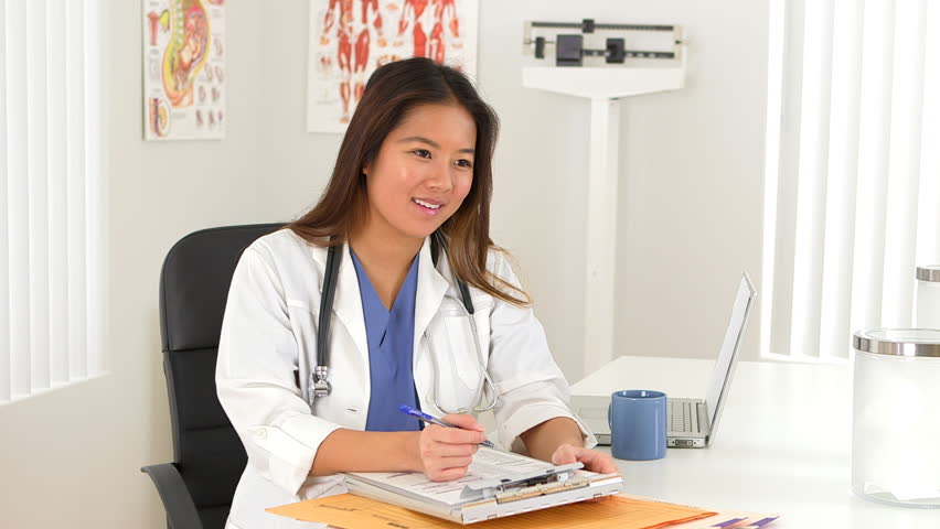 Female Asian doctor talking to client at desk