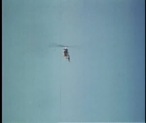 Stuntman hanging onto landing gear of helicopter in flight