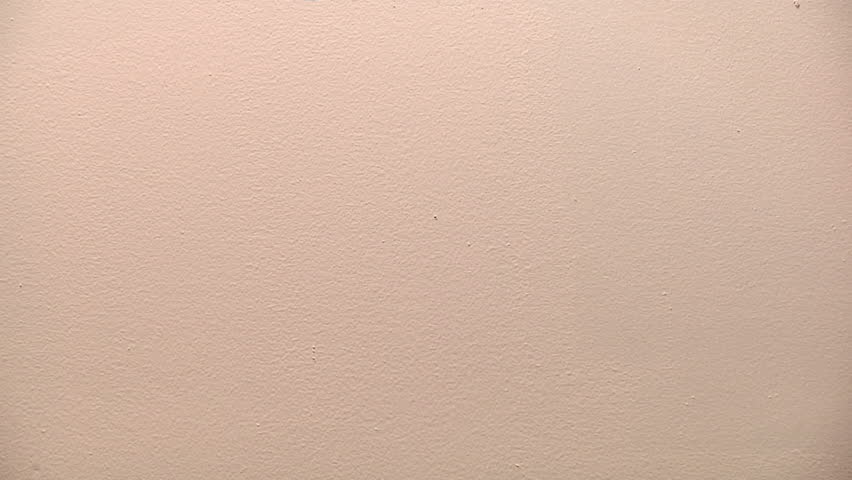 painter rolls red paint onto a white wall