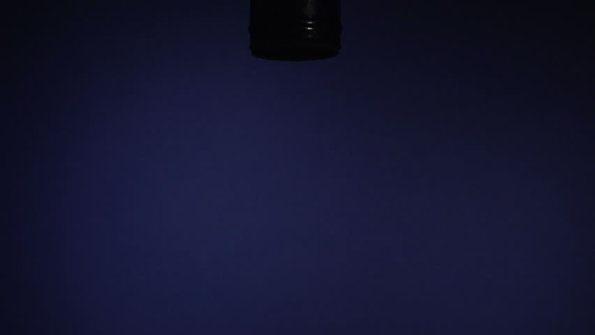 hand screws in a cfl lightbulb on a blue background