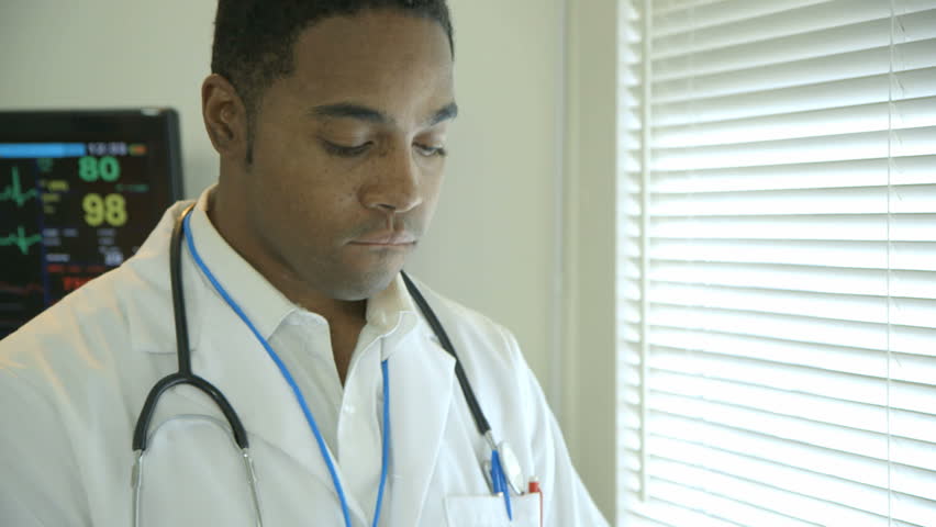 A young African American physician standing by a window slowly become encouraged