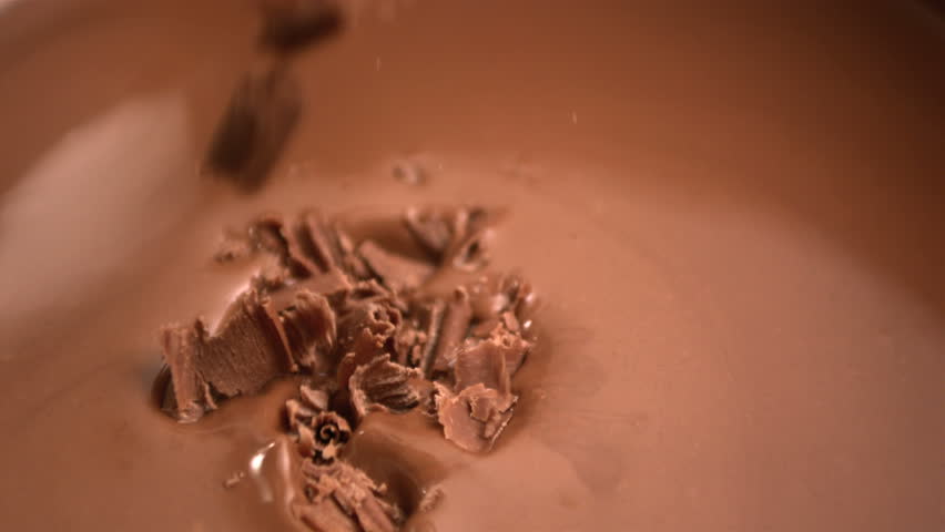 Chocolate flakes falling into melted chocolate in slow motion