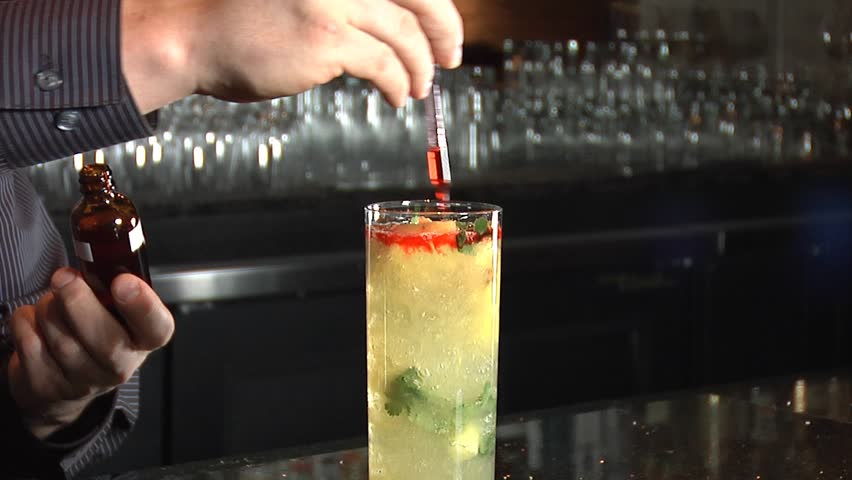 Bartender flavors a cocktail/ Pineapple beverage is garnished by bartender