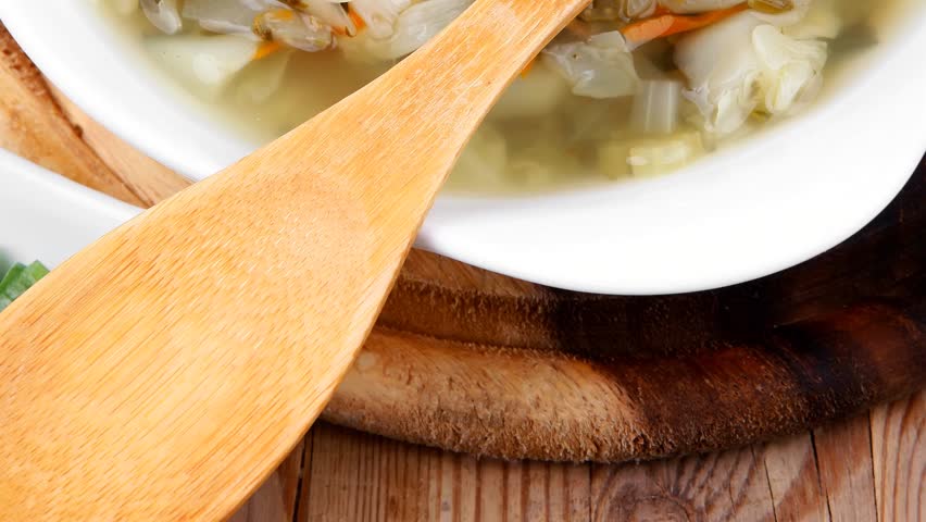 diet food : hot vegetable soup with bread crackers in white bowl on wood stand over table