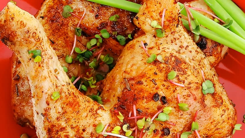 meat food : grilled quarter chicken garnished with green sprouts and red peppers on red plate hidef slow motion intro