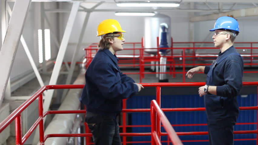 Two workers talking about a job in a factory, controls the operation of devices in a power plant