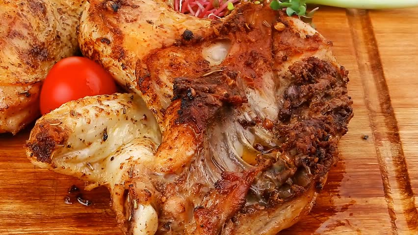 meat food : roasted chicken legs garnished with green sprouts and peppers on wooden plate hidef slow motion intro
