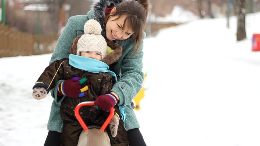 Happy family. Mother and baby balancing on a seesaw in playground