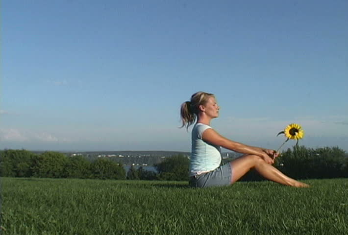 Video of a girl who feels finally free at last and holding a sunflower in a park with plenty of space to ad your own elements
