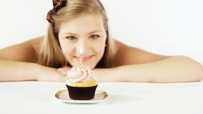 close up of a young girl blowing a single candle on op of a cup cake _dolley_