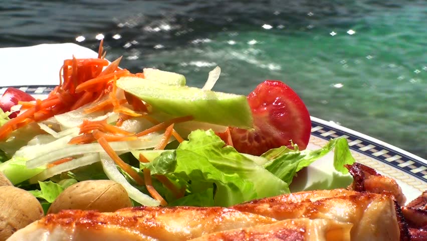 Seafood salad with squid and fresh vegetable on sea background