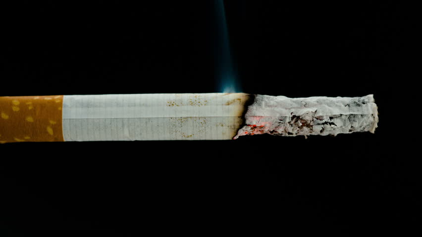 Burning cigarette on black background in stop motion