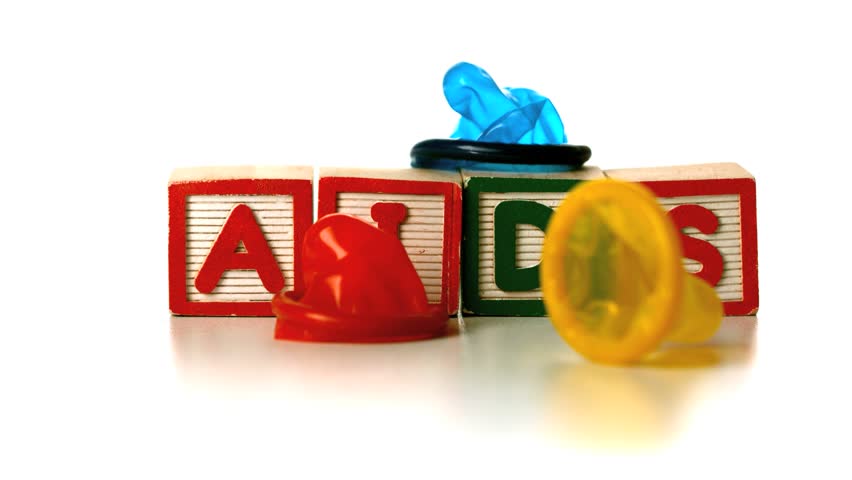 Colourful condoms falling on blocks spelling AIDS in slow motion