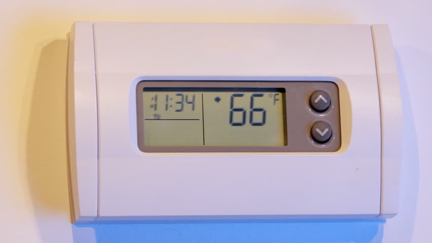 Close up of woman's hand coming into frame, raises and lowers temperature on wall thermostat, shot in HD video