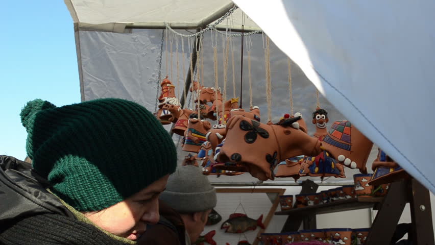 VILNIUS, LITHUANIA - MARCH 02: Crockery clay handmade cow objects decorations hang in outdoor spring fair market festival tent and customers choose them on March 02, 2012 in Vilnius.