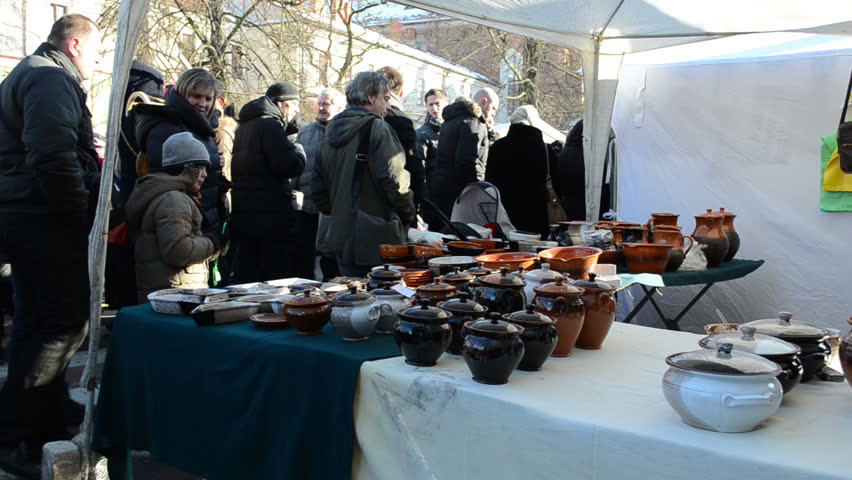 VILNIUS, LITHUANIA - MARCH 02: People walk near handmade crockery clay craft pots sell in outdoor street fair market on March 02, 2012 in Vilnius. National spring fair event.
