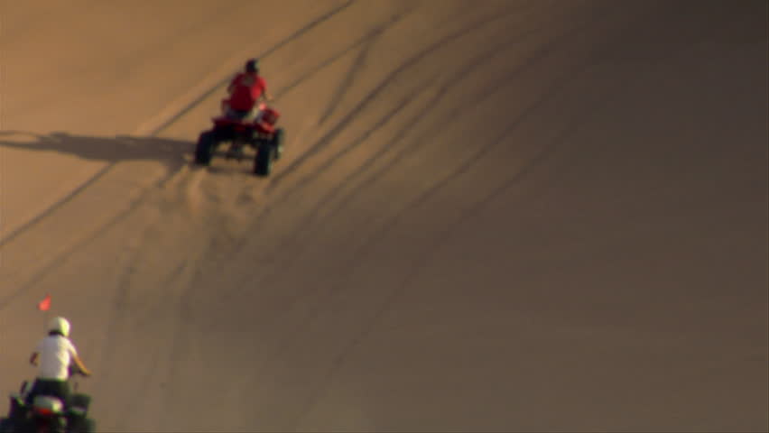 ATV riders climb enormous sand dune