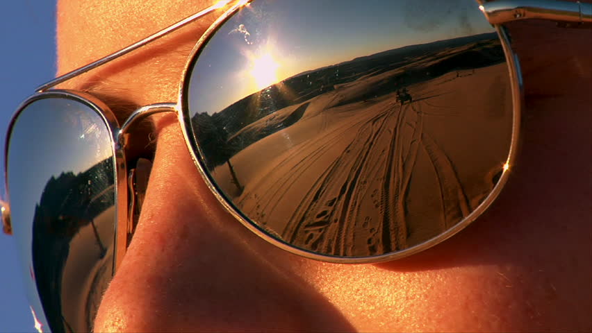 ATV riders on sand dunes reflected in sunglasses