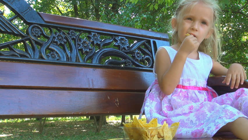Little Girl Eating Cornflakes on Bench in Park, Child Eats Cereals, Children
