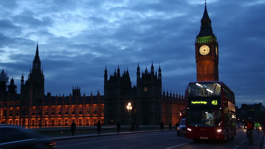 LONDON - MARCH 13: Buses, cars and pedestrians cross Westminster Bridge at night with Houses of Parliament in the background on March 13, 2013 in London. The Palace of Westminster is a UNESCO site.