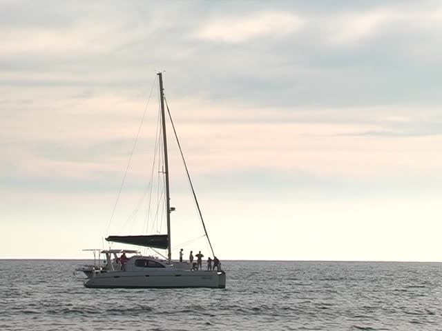 Catamaran sailing away on the ocean,