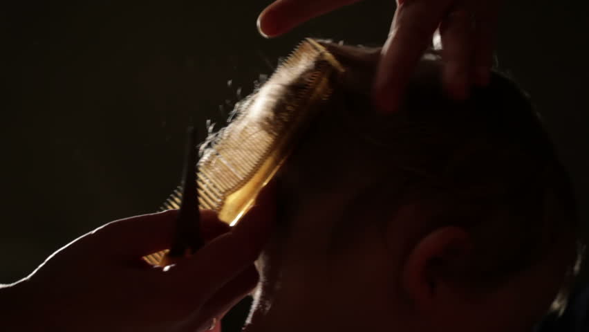 The little boy's hair is being cut. Back light.