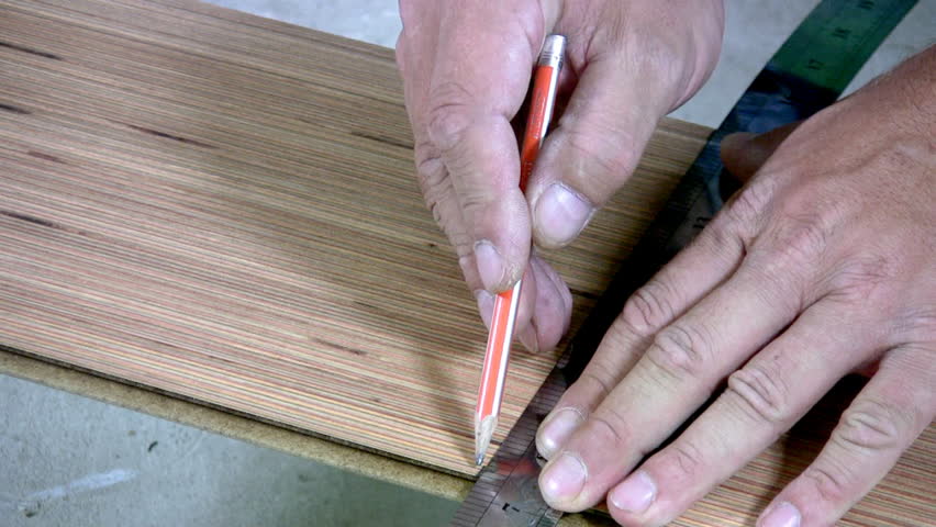 Men's hand draw a pencil line on the laminate. Men's hands are doing sawing with an electric hand-sawing