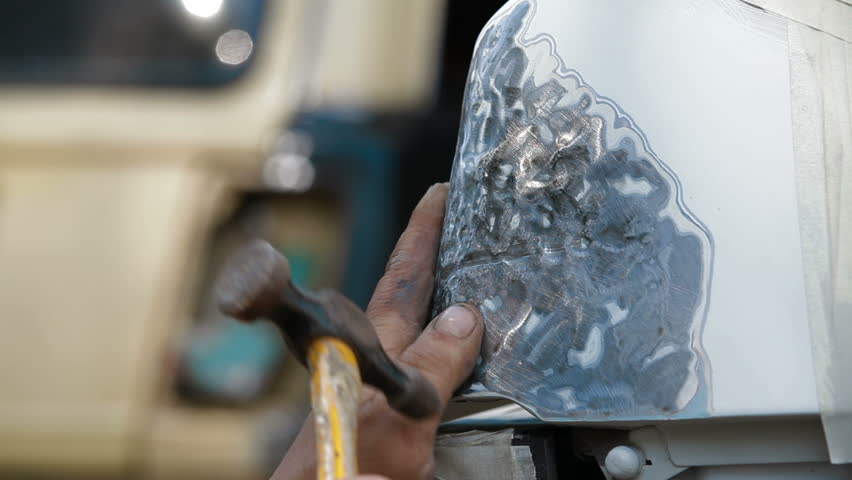 A man is preparing damaged car surface for smearing putty by smoothing it. Original sound included.