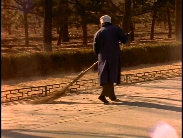 China, woman sweeping with primitive broom made of tree branches