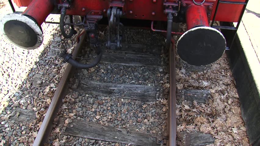 Traditional buffer-and-chain coupler, steam locomotive riding backwards and bumps.