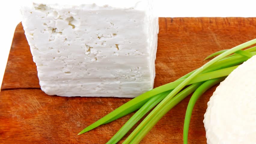 dairy food : feta white cheese cubes on cut wooden plate isolated over white background