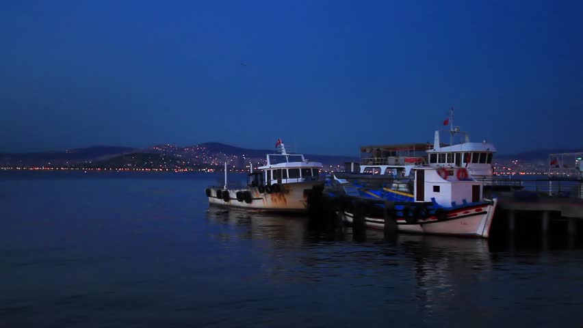 Fisher boats at berth in shore of Buyukada Island. Night scene with city lights on Islands
