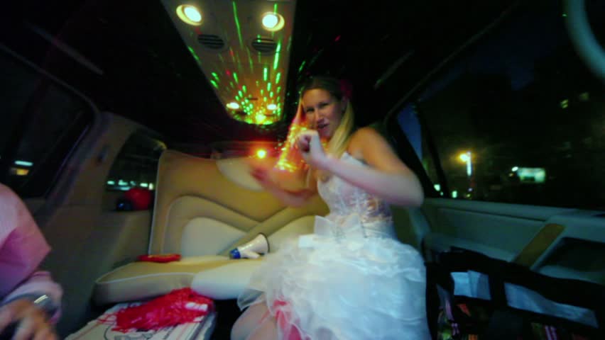 Bride in wedding dress dances and groom takes loudhailer during ride in limo