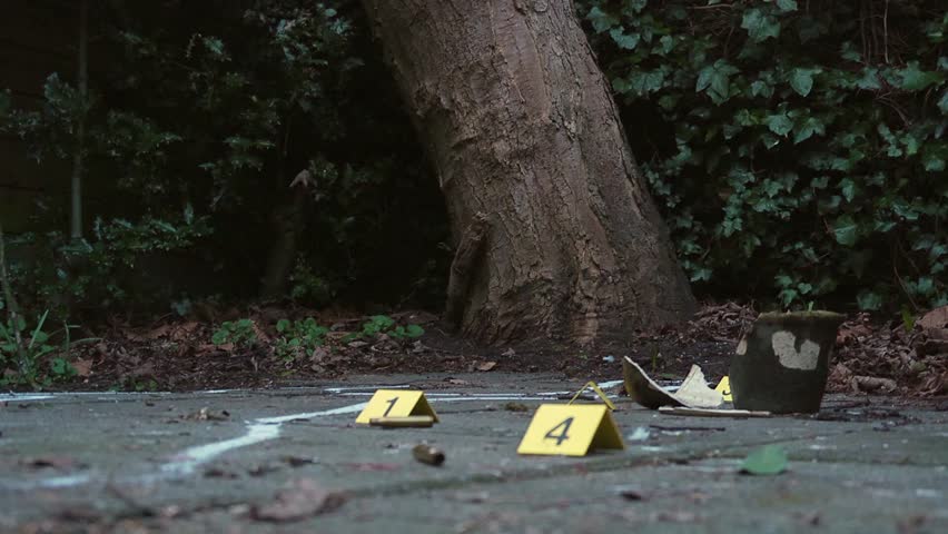 Forensics police investigator marking a rifle casing with a white chalk circle during his investigations at a crime scene