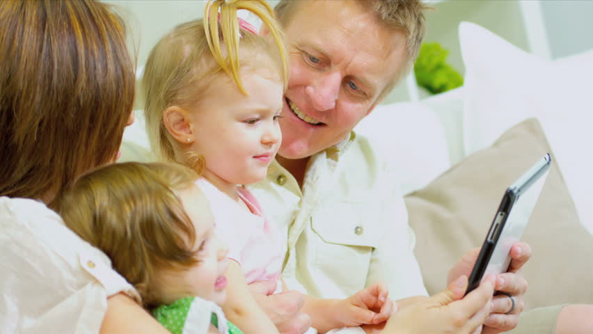 Young Caucasian girls having fun modern wireless tablet with parents shot on RED EPIC