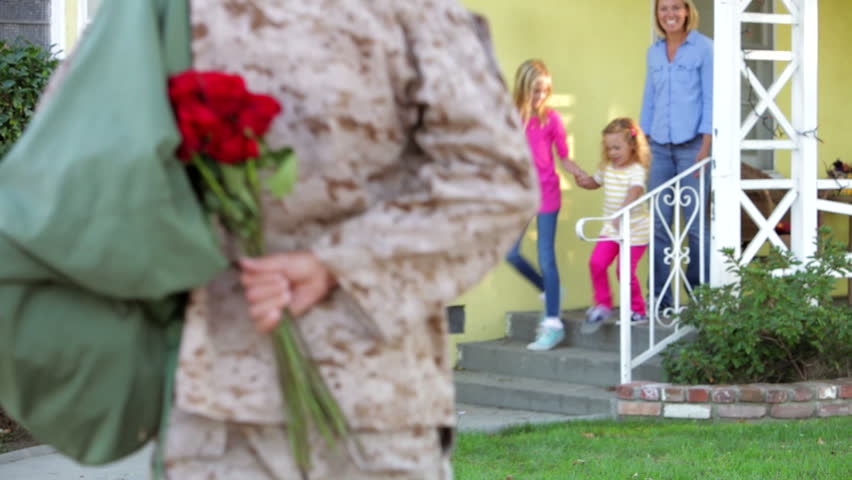 Family rushes to greet army husband returning on leave - he gives them flowers and they hug. Shot on Canon 5d Mk2 with a frame rate of 30fps