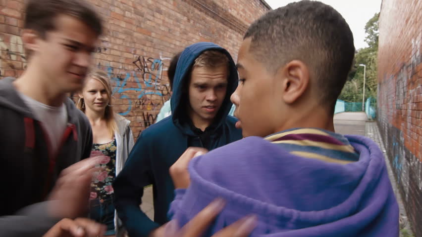 Teen bullying - a group of teenagers attack one boy