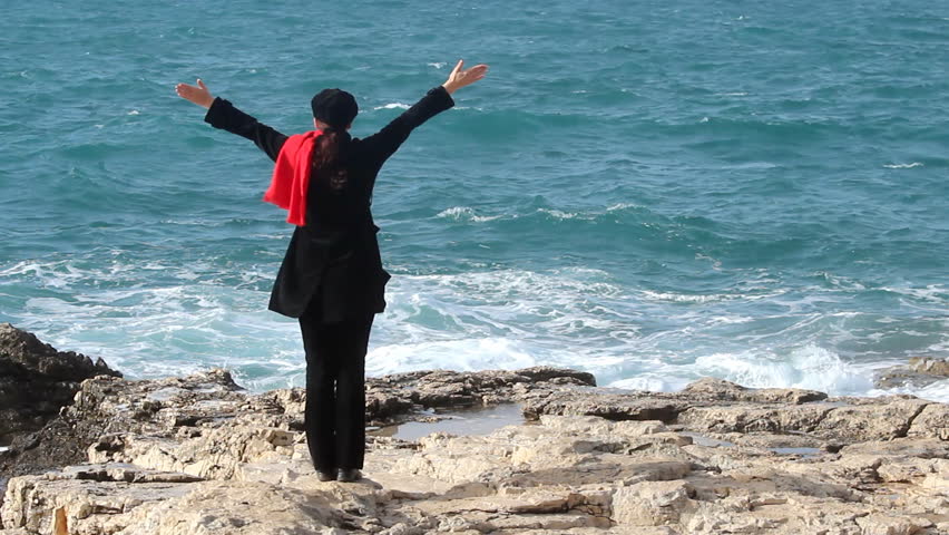 Praising the sea - Woman lifting hands in the air by the sea.

