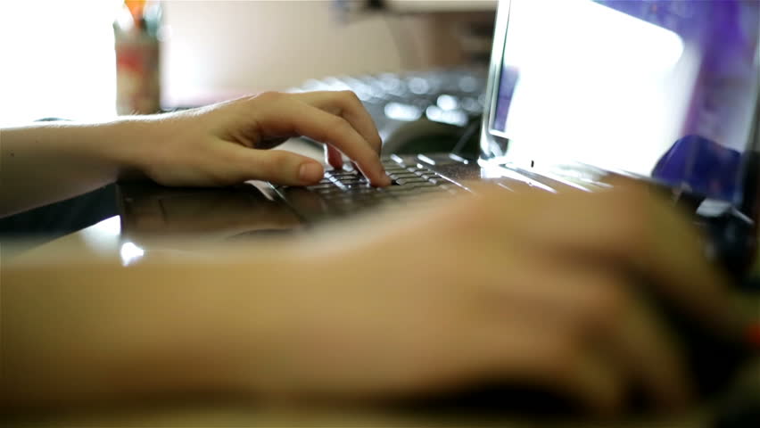 A young boy playing an online game on his personal computer. Close-up on his hands and fingers pushing the keyboard buttons.