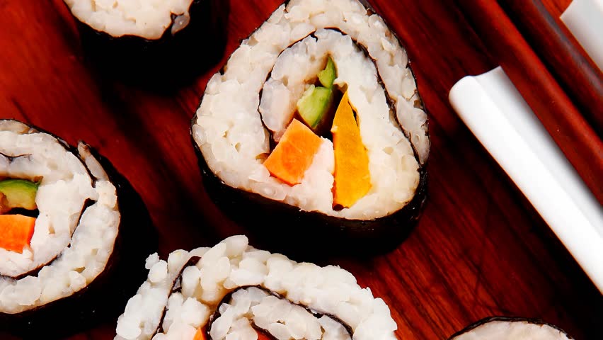 Japanese traditional Cuisine - Roll with Cucumber Cream Cheese with raw Tuna(maguro) and Salmon(sake) inside. on wooden plate with wasabi and ginger isolated over white background