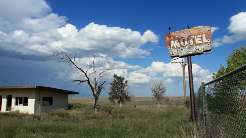 Timelapse of clouds behind an old, creepy, abandoned motel in rural Colorado, complete with bullet-holes in Motel sign, old tree, and gutted building.  HD 1080p Time lapse.