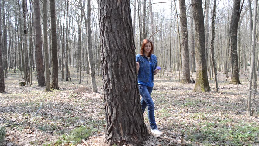 beautiful girl standing near the tree in the hand holds out the wildflowers