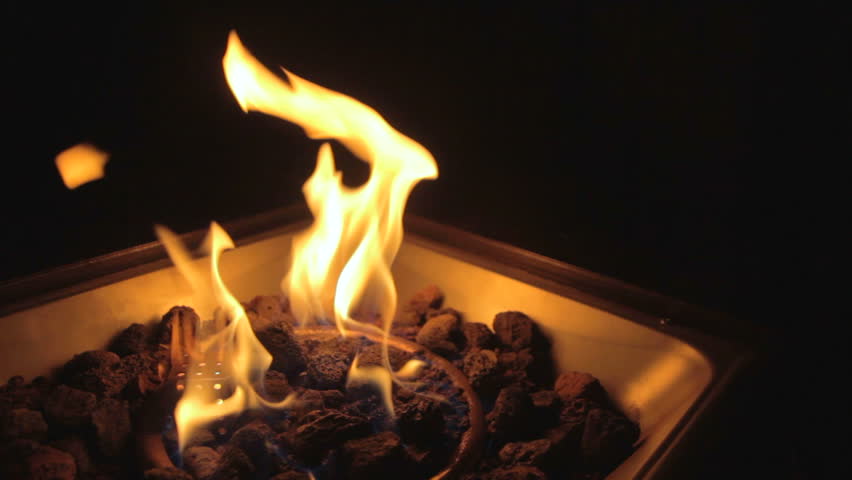 A propane gas fire pit at night.