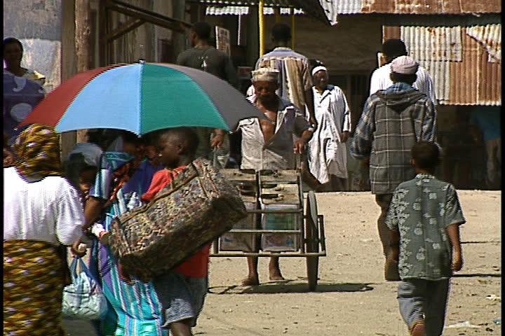DAR ES SALAAM, TANZANIA - DECEMBER 1, 1998: Pedestrians and man pushing cart.