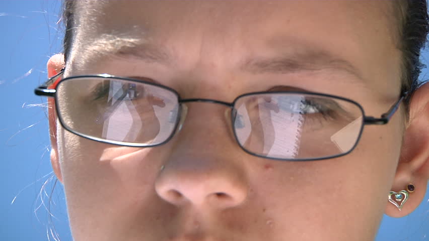 Student studying - her writing reflected in her glasses